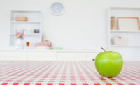 An apple on a tablecloth in a kitchen