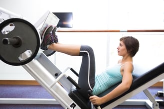 Fit brunette using weights machine for legs at the gym