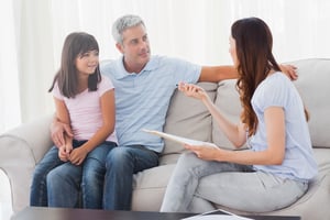 Parents with their daughter sitting on sofa at home