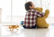 Portrait of child sitting in living room with Teddy bear