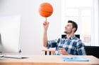 Happy businessman in casual cloth sitting at the table and spinning ball in office